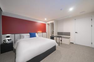 um quarto com uma cama branca e uma parede vermelha em Hotel Lavanda em Incheon