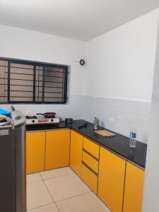 une cuisine avec des armoires jaunes et un comptoir noir dans l'établissement Laasya Comforts, à Mangalore