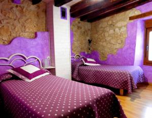 two beds in a room with purple walls at Casa Rural 1904 in Tubilla del Lago