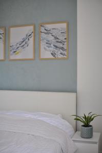 Un dormitorio con una cama blanca con tres cuadros en la pared. en Apartament Verano, en Gdansk