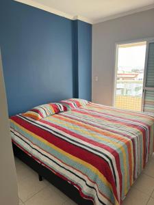 een bed met een kleurrijke deken erop in een kamer bij Pé na areia Fábio e Silvia in Praia Grande