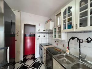 uma cozinha com um lavatório e um frigorífico vermelho em Melanie- City Centre Apartment em Herceg Novi