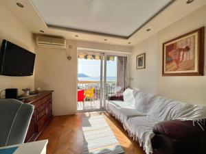 een woonkamer met een bank en een balkon bij Melanie- City Centre Apartment in Herceg-Novi