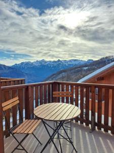 una mesa de madera y una silla en un balcón con montañas en - Appartement avec balcon - 2 personnes en Puy-Saint-Vincent
