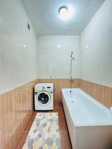 a bathroom with a washing machine and a tub at Супер квартира для большой семьи in Almaty