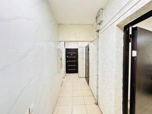 a hallway with white walls and a black door at Супер квартира для большой семьи in Almaty