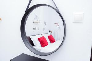 un espejo colgado en una pared con almohadas rojas en WhiteHome Apartment en Xanthi