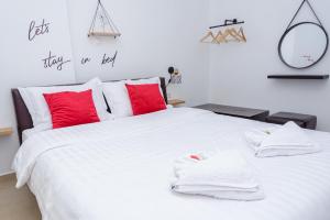 a bedroom with a large white bed with red pillows at WhiteHome Apartment in Xanthi