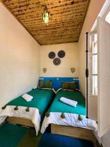 two beds in a small room with green sheets at Riyad zen oasis in Essaouira +30 photos