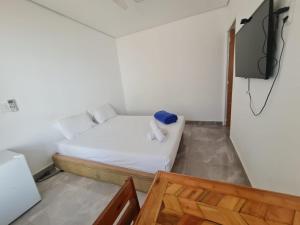 a small bedroom with a bed and a tv at Wafeh Fleming Suítes Pampulha in Belo Horizonte