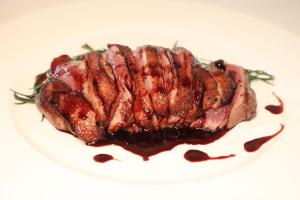 a piece of meat on a white plate with sauce at Il Podere Del Germano Reale in Coriano