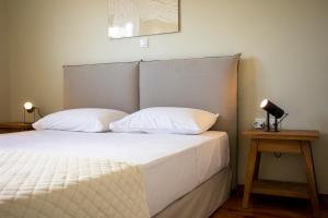 a bed with two pillows and a lamp on a table at Oinopia Apartments in Egina