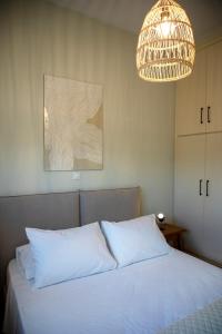 a bedroom with a white bed and a chandelier at Oinopia Apartments in Aegina Town