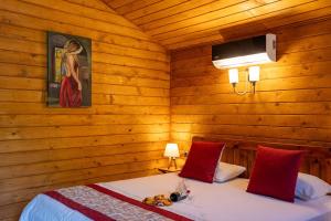 a bedroom with wooden walls and two beds with red pillows at Eden Bungalows and Beach in Koycegiz