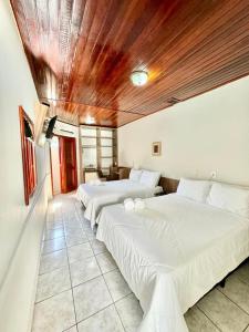a bedroom with two beds and a wooden ceiling at Hotel Arrastão in São Sebastião