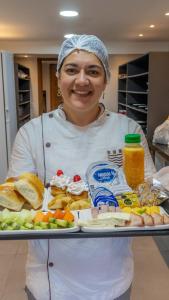 Eine Frau hält ein Tablett mit Essen. in der Unterkunft Kastel Petrópolis in Petrópolis