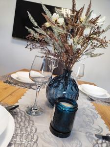 een tafel met een blauwe vaas met bloemen en wijnglazen bij Apartment Ruža in Trogir