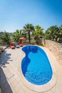 a swimming pool in a patio with palm trees at 3 Bedroom Holiday Home with Private Pool and Views in Nadur