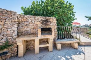 a stone wall with a table and two benches at 3 Bedroom Holiday Home with Private Pool and Views in Nadur