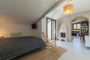 1 dormitorio con 1 cama y sala de estar con chimenea en Les jardins de Lamourelle, en Lacquy
