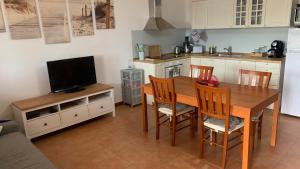 a kitchen with a wooden table with chairs and a television at Eden Rock House in Domus de Maria