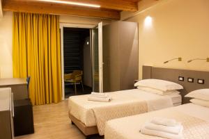 ein Hotelzimmer mit 2 Betten und gelben Vorhängen in der Unterkunft KRINÒ hotel in Augusta