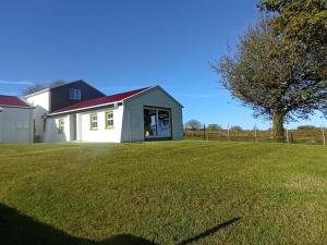 una casa bianca con un tetto rosso su un cortile di Tiernan's Luxury Cottages a Newtown-Dillon