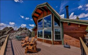 a cabin with a deck with chairs and a large window at 273 Fallen Rock in Tabernash