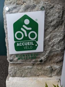 una señal en el costado de una pared con una señal para una bicicleta en Auberge Des Pins, en Aubenas