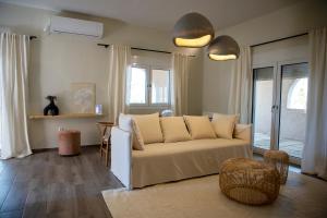 Una sala de estar con un sofá blanco y algunas ventanas. en Oinopia Apartments, en Aegina Town