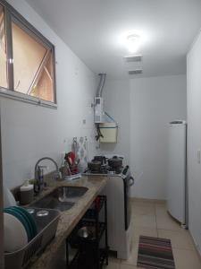 una pequeña cocina con fregadero y nevera. en Loft no Recreio, en Río de Janeiro