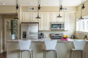 a kitchen with white cabinets and white bar stools at The Bywater in New Orleans