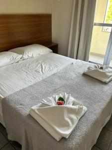 Una cama blanca con una cesta de flores. en Piúma Palace Hotel, en Piúma
