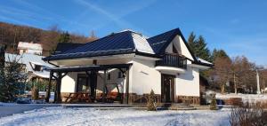 a house with a solar roof in the snow at Apartmánový dom PRAMEŇ in Vinné