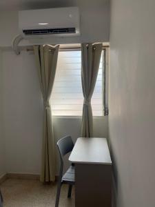 Habitación con escritorio y ventana con cortinas. en Habitaciones privadas en un departamento encantador, en Panamá