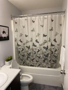 a bathroom with a toilet and a shower curtain with butterflies at Exquisite Guest suite in Saskatoon in Saskatoon