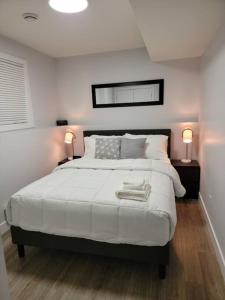 a bedroom with a large white bed with two lamps at Exquisite Guest suite in Saskatoon in Saskatoon