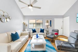 uma sala de estar com um sofá branco e almofadas azuis em Beach Road Condo, Private Deck, Siesta Key Village and Beach Walkable em Siesta Key