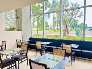 um restaurante com mesas, cadeiras e janelas em Naoum Hotel em Brasília