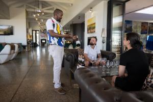 a man standing in a bar holding a bottle of wine at Water, views, vineyards, The Zen in Hermanus