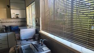 a kitchen with a window with blinds over a sink at Sharing is Caring in Mahikeng