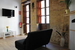 uma sala de estar com uma cadeira preta e uma parede de tijolos em Las Arenas Suites 2 em Valência