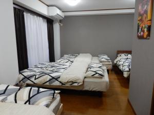 3 bedden staan in een kamer bij クレインネスト201貸切9人部屋民泊 海遊館2分、USJ25分無料駐車場 in Osaka