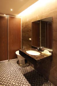 een badkamer met een wastafel, een toilet en een spiegel bij Sankaikan Hotel in Puzi