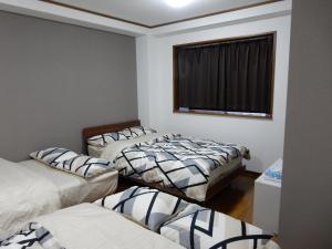 een kamer met 3 bedden en een raam bij クレインネスト201貸切9人部屋民泊 海遊館2分、USJ25分無料駐車場 in Osaka