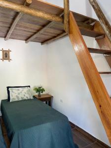 sypialnia z zielonym łóżkiem i drewnianym sufitem w obiekcie Vila do Surfe w mieście Ubatuba