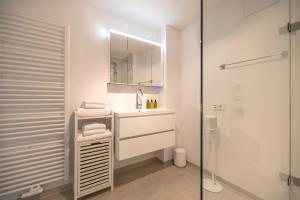 ein weißes Badezimmer mit einem Waschbecken und einem Spiegel in der Unterkunft Reethus Keitum in Keitum