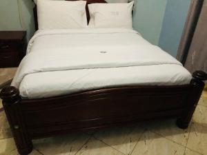 Una cama con sábanas blancas y almohadas. en Gorilla Homestay Kabale en Kabale
