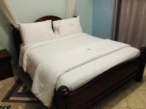 1 cama con sábanas blancas y almohadas en una habitación en Gorilla Homestay Kabale en Kabale