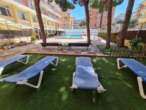 a group of blue benches in a courtyard with a pool at Beta's Beach in Blanes